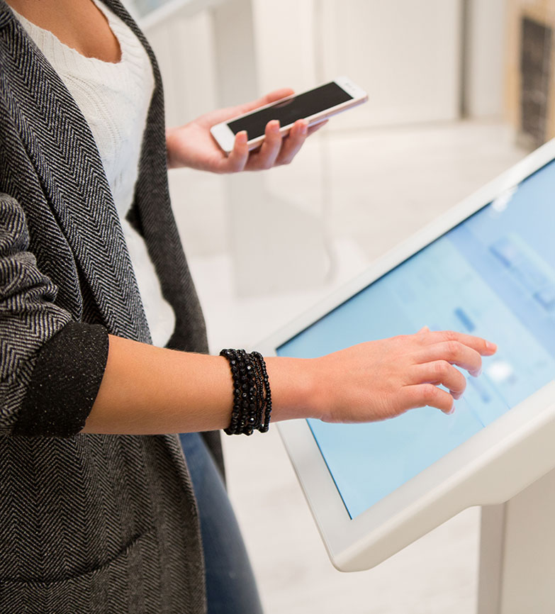 lady with her cell phone at a high-tech kiosk