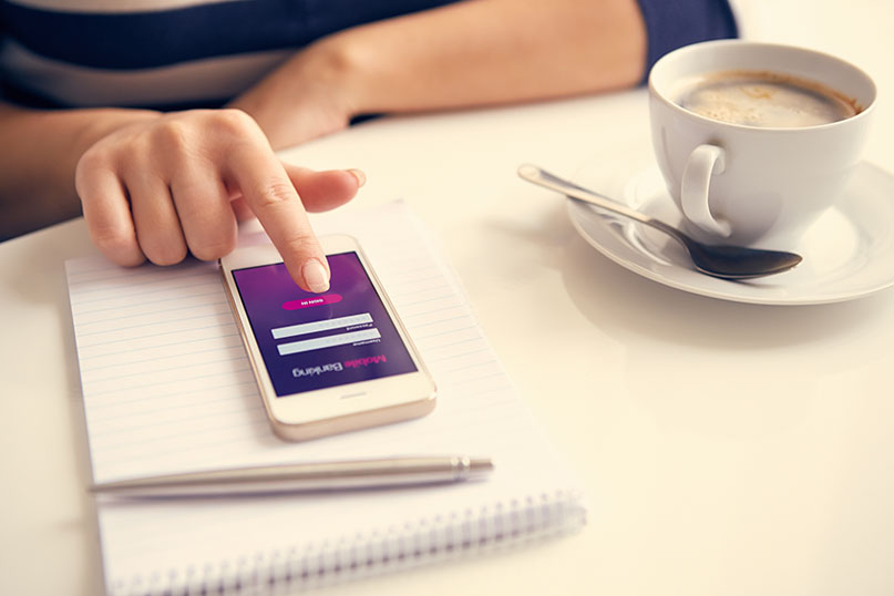 photo of woman using app on phone next to a cup of coffee